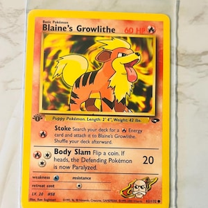 以下が含まれることがあります： 黄色いブーメランズ・グロウライツのポケモンカード。オレンジと黄色の毛皮を持つグロウライツのイラストが描かれています。カードには、ポケモンの名前、HP、攻撃の詳細などのテキストがあります。カードの長さは71cm、重さは19kgです。