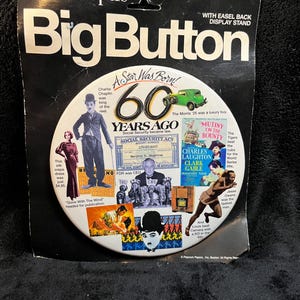 May include: A vintage "Big Button" display stand from Peacock Papers. The button features images and text celebrating "60 Years Ago," including Charlie Chaplin, a green car, and references to "Gone With The Wind."