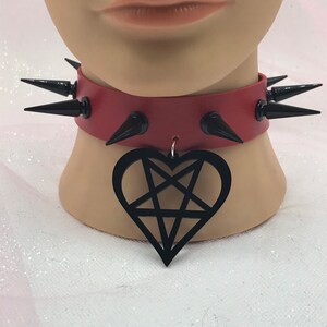 May include: A red leather choker with black spikes and a black heart-shaped pendant with a pentagram inside.