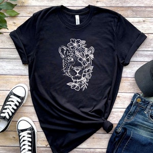 May include: Black t-shirt with a white graphic of a jaguar's face surrounded by flowers.