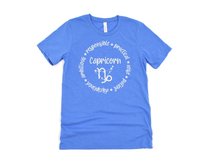 May include: A blue t-shirt with a white circle design featuring the zodiac sign Capricorn and the words "Capricorn", "ambitious", "responsible", "practical", "patient", "wise", "determined", "grounded".