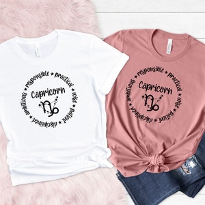 May include: Two t-shirts with a black circle design featuring the Capricorn zodiac symbol and the words "Capricorn", "ambitious", "responsible", "practical", "wise", "patient", and "disciplined".