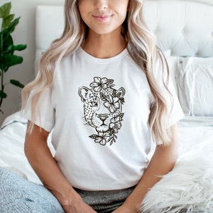 May include: White t-shirt with a black and white illustration of a leopard's face surrounded by flowers.