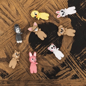 Puede incluir: Una colecci&oacute;n de peque&ntilde;as figuras de animales de colores, que incluyen un pollito amarillo, un conejo blanco, un lobo gris, un oso marr&oacute;n, un conejito rosa y un oso blanco. Las figuras est&aacute;n sobre una superficie de madera.