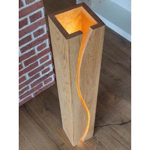 May include: A tall, wooden floor lamp with a curved, open design. The lamp is made of natural wood and has a warm, glowing light.