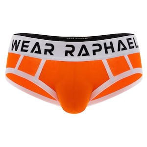 Puede incluir: Calzoncillos naranja con ribete blanco y el texto "WEAR RAPHAEL" en negro.