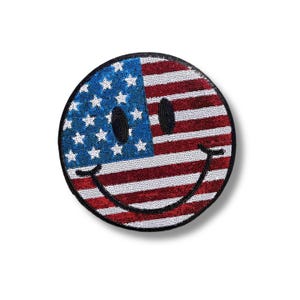 May include: A round, black-outlined smiley face patch with the American flag design in red, white, and blue sequins.