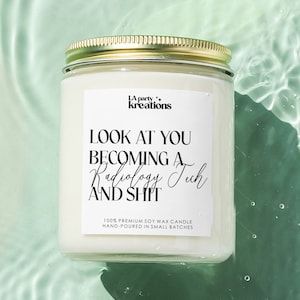 May include: A white soy wax candle with a gold lid. The candle has a black label with the text "LA party+ kreations" and "LOOK AT YOU BECOMING A Radiology Tech AND SHIT". The label also includes the text "100% PREMIUM SOY WAX CANDLE HAND-POURED IN SMALL BATCHES".