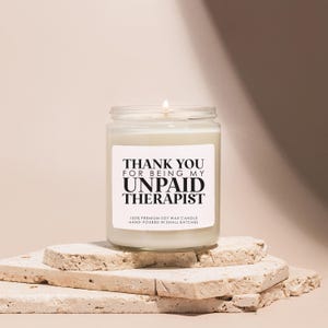 a white candle sitting on top of a pile of rocks