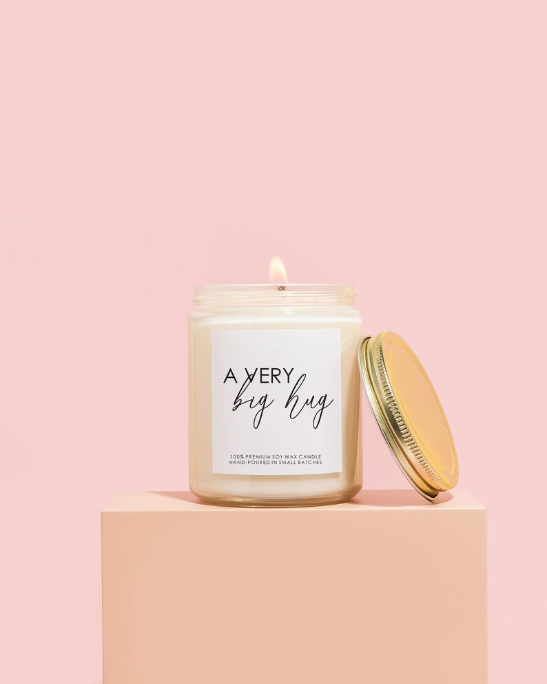 a jar of a candle sitting on top of a pink block