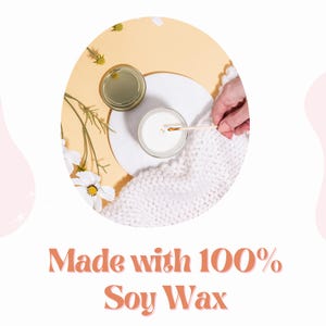 May include: A white soy wax candle with a gold lid is lit and sitting on a white marble plate. The candle is surrounded by white flowers and a white knitted blanket. The text "Made with 100% Soy Wax" is written in orange letters on a white background.