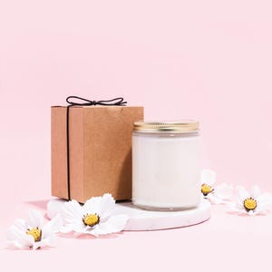 a white candle and a brown box on a pink background