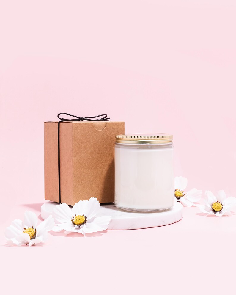 a white candle and a brown box on a pink background