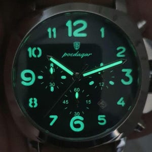 May include: A black chronograph watch with luminous green hands and numbers. The watch face has the brand name "poedagar" printed on it.
