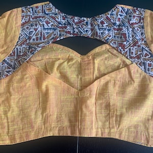 May include: A yellow cotton blouse with a geometric pattern on the sleeves and a keyhole back opening.