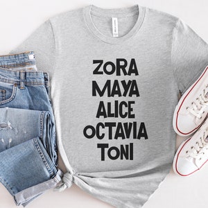 May include: A gray t-shirt with the names Zora, Maya, Alice, Octavia, and Toni printed in black letters.