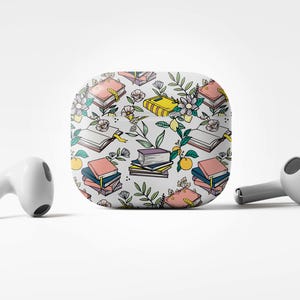 Op de afbeelding: Een witte draadloze oplaadcase met een kleurrijk patroon van boeken, bloemen en citroenen. De case is ontworpen om draadloze oordopjes in op te bergen.