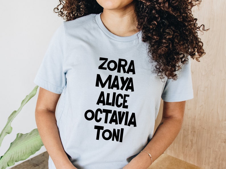 May include: A light blue t-shirt with black text that reads "Zora Maya Alice Octavia Toni".