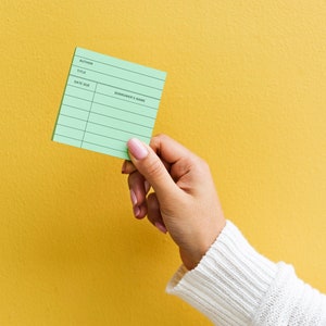 May include: A green library card with lines for author, title, date due, and borrower's name.