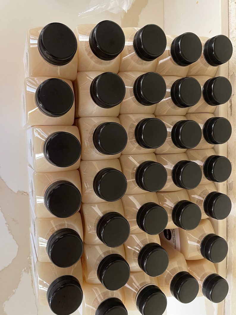 May include: A close-up view of a stack of 48 clear plastic bottles with black lids. The bottles are filled with a light-colored liquid.