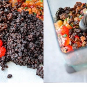 May include: A close-up of a mixture of dried fruits and candied cherries, some of which are in a blender. The mixture includes red candied cherries, dark raisins, and other dried fruits.