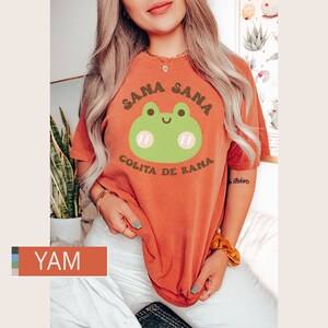 Puede incluir: Una camiseta naranja quemada con un gr&aacute;fico de rana verde y el texto "Sana Sana Golita de Rana".