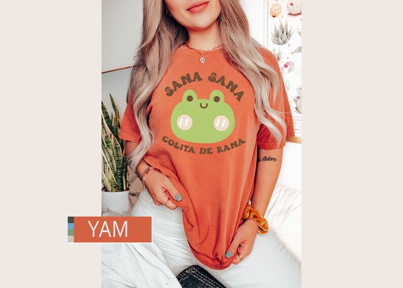 Puede incluir: Una camiseta naranja quemada con un gr&aacute;fico de rana verde y el texto "Sana Sana Golita de Rana".