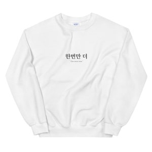 Peut inclure: Sweat-shirt blanc avec l'expression coréenne "한번만 더" et la traduction anglaise "One more time" imprimée sur le devant.