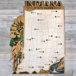May include: A wooden map of Indiana with the state's name and "State Parks" printed at the top. The map is outlined in black and shows the locations of various state parks throughout the state. A small cardinal is depicted on the left side of the map.
