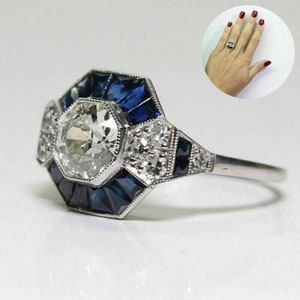 May include: A silver ring featuring a large octagon-shaped centre stone surrounded by smaller blue and white stones.