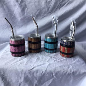 May include: Four stainless steel tumblers with barrel-style designs. Each tumbler has a different color scheme: pink, brown, blue, and red with a stars and stripes pattern. Each tumbler includes a stainless steel straw.