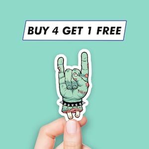 May include: A sticker of a green zombie hand giving the rock and roll hand gesture. The hand is wearing a black studded bracelet. The sticker has the text "BUY 4 GET 1 FREE" at the top.