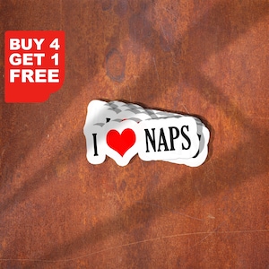 Può includere: Adesivi bianchi con la scritta "I ❤️ NAPS" e un cuore rosso. Un elemento grafico rosso nell'angolo dice "BUY 4 GET 1 FREE". Gli adesivi sono su una superficie marrone arrugginita.