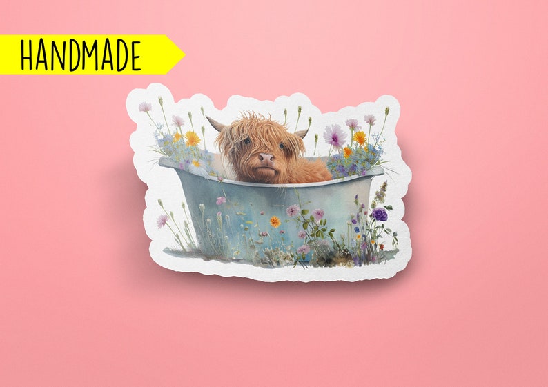 May include: A handmade sticker featuring a Highland cow taking a bath in a tub filled with wildflowers. The cow is brown and white with a fluffy coat. The tub is blue and white with a rustic look. The flowers are a variety of colors, including pink, purple, yellow, and white.
