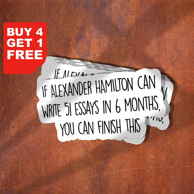 May include: A stack of white stickers with the text "IF ALEXANDER HAMILTON CAN WRITE 51 ESSAYS IN 6 MONTHS, YOU CAN FINISH THIS" in black text. The stickers are on a rusty brown surface. The text "BUY 4 GET 1 FREE" is in red text on a white background.