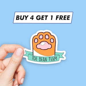 Peut inclure: Un autocollant avec une empreinte de patte de dessin animé en orange et rose avec un ruban turquoise qui dit "Toe Bean Team". L'autocollant a une bordure blanche et est tenu par une main. Le texte "BUY 4 GET 1 FREE" est dans un rectangle blanc avec une bordure bleue.