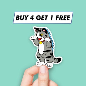 May include: A gray and white cat wearing a blue dinosaur costume with a red collar and a yellow tag. The cat is standing on its hind legs with its front paws raised. The text "BUY 4 GET 1 FREE" is above the cat.