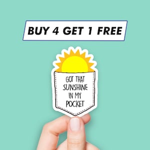 May include: A white pocket with a yellow sun peeking out of the top. The pocket has the text "Got that sunshine in my pocket" written inside.