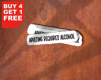 May include: White sticker with the text "ADULTING REQUIRES ALCOHOL" on a textured brown background. A red corner graphic reads "BUY 4 GET 1 FREE". The sticker has a jagged edge design.