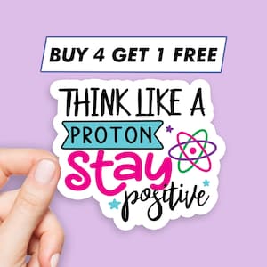 Può includere: Un adesivo bianco con il testo "Think like a proton stay positive" in lettere nere, rosa e blu. L'adesivo presenta anche un simbolo di atomo stilizzato in verde, rosa e blu.