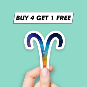 Könnte beinhalten: Ein weißer Aufkleber mit einem Regenbogen-Galaxie-Design innerhalb der Form des astrologischen Symbols für Widder. Der Aufkleber trägt den Text "BUY 4 GET 1 FREE" darüber.