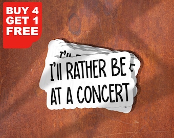 May include: A stack of white stickers with the text "I'll rather be at a concert!" in black lettering. The stickers are on a rusty brown surface. The text "BUY 4 GET 1 FREE" is in red lettering on a white background in the top left corner of the image.
