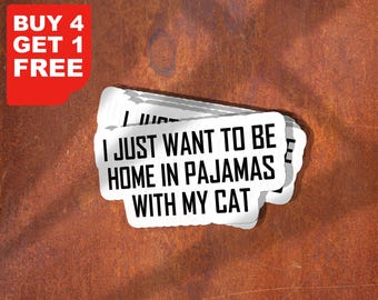 Può includere: Una pila di adesivi bianchi con la scritta "I JUST WANT TO BE HOME IN PAJAMAS WITH MY CAT" in grassetto nero. Un elemento grafico rosso nell'angolo dice "BUY 4 GET 1 FREE". Lo sfondo è marrone ruggine strutturato.