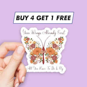 May include: A white sticker with a butterfly design. The butterfly is made of flowers in shades of orange, pink, and white. The text "Your Wings Already Exist" is above the butterfly and the text "All You Have To Do Is Fly" is below the butterfly.