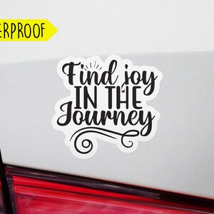 May include: White car with a black vinyl sticker that says "Find joy in the journey".