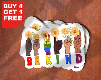 May include: A stack of white stickers with the words "BE KIND" spelled out in colorful letters using American Sign Language. The stickers feature illustrations of hands, sunflowers, and the text "BUY 4 GET 1 FREE" in a red box.