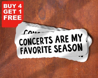 May include: A white sticker with black text that reads "Concerts are my favorite season". The sticker is slightly curled at the edges and has a rough, textured surface.