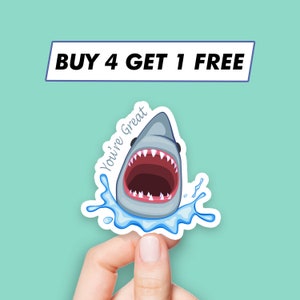 May include: A white shark sticker with an open mouth and the text "You're Great" on a blue water background. The sticker has a white border.