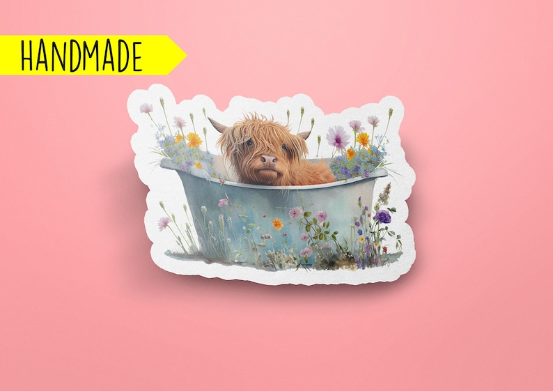 K&ouml;nnte beinhalten: Ein handgemachter Sticker mit einer Highland-Kuh, die in einer mit Wildblumen gef&uuml;llten Wanne ein Bad nimmt. Die Kuh ist braun und wei&szlig; mit einem flauschigen Fell. Die Wanne ist blau und wei&szlig; mit einem rustikalen Look. Die Blumen sind in verschiedenen Farben, darunter rosa, lila, gelb und wei&szlig;.