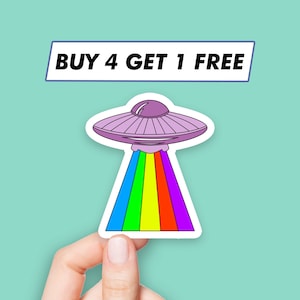 Może przedstawiać: Naklejka z różowym UFO strzelającym wiązką światła tęczy. Na naklejce widnieje napis "BUY 4 GET 1 FREE" u góry.
